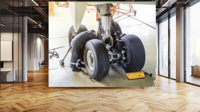 Repair of the chassis landing gear of the aircraft, two technicians of mechanics at work in the hangar. Wall mural