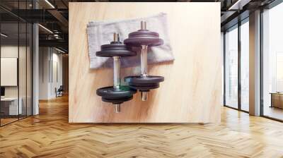 Two dumbbells lie on the floor with a towel, home workout. Wall mural