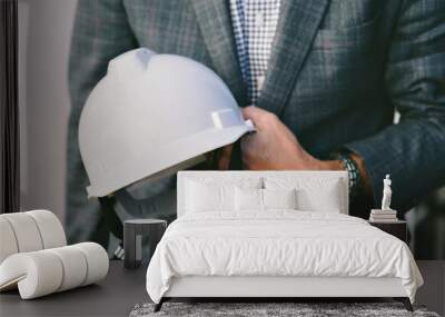 Businessman holds a white hard hat while wearing a business suit Wall mural