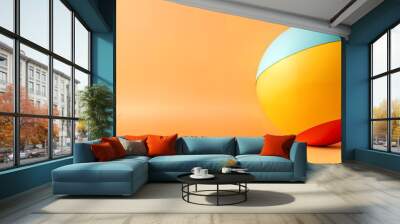 Abstract orange colored background. Large multicolored ball resting on a flat surface. The ball has three horizontal stripes in light blue, yellow and red.  Wall mural