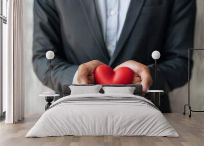 A man is holding a red heart in his hand. Concept of love and affection Wall mural