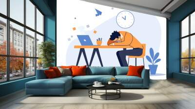 A man is sitting at a desk with a laptop and a clock. He is looking at the clock and he is tired Wall mural