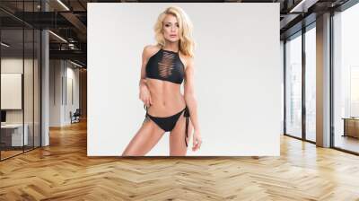 Sexy blonde woman in black swimwear over grey background Wall mural