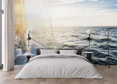 Yacht sailing in an open sea at sunset. Close-up view of the deck, mast and sails. Clear sky after the rain, glowing clouds, golden sunlight. Panoramic seascape Wall mural