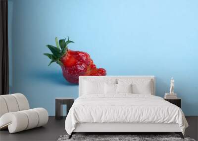 Ugly organic strawberry berry on a light blue background. Place for text Wall mural