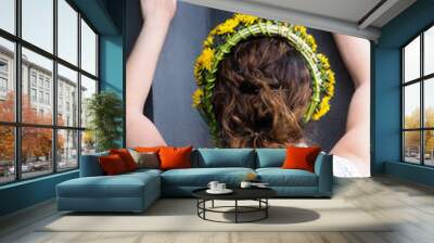 Woman stretching against a grey wall with a flower wreath in bea Wall mural