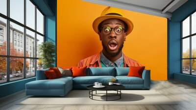 Capture the expression of awe on a casually dressed male with stylish clothing, Create a portrait shot against a colorful background, emphasizing the surprised and intrigued expression on his face. Wall mural