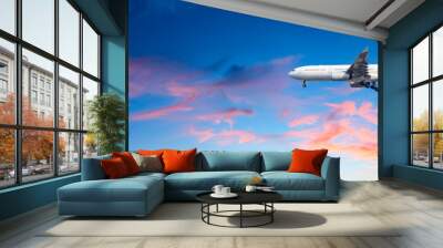 Airplane flying above dramatic clouds during sunset Wall mural