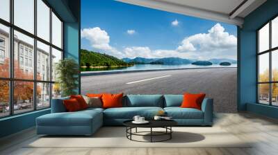 Asphalt highway road and lake with mountains nature landscape on a sunny day. Beautiful coastline in summer season. Wall mural