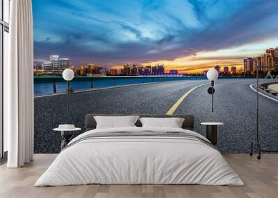 Asphalt road and city skyline with modern building at sunset in Suzhou, China. Wall mural