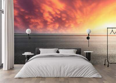 Asphalt road and dramatic sky with coastline at sunset Wall mural