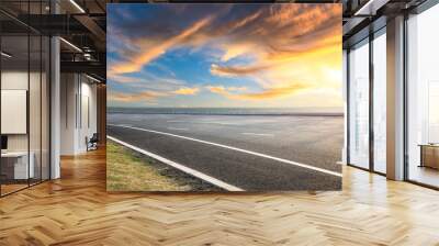 Asphalt road and dramatic sky with coastline at sunset Wall mural