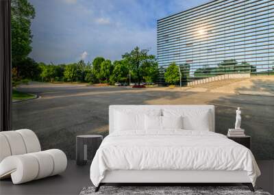 Asphalt road and green forest with glass wall building background in city park Wall mural