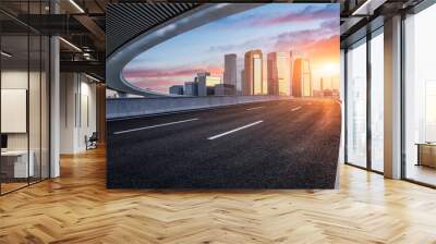 Asphalt road and urban skyline with modern buildings at sunrise Wall mural