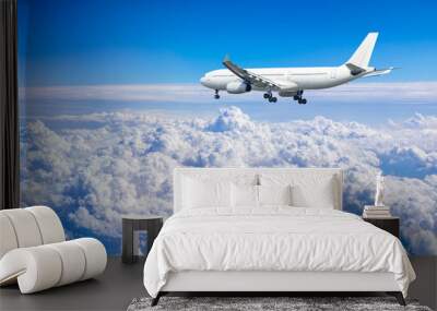 Commercial airplane flying above blue sky and white clouds. Wall mural