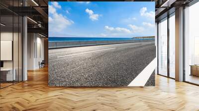 Empty asphalt road near the lake under blue sky Wall mural