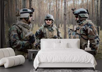 A group of middle-aged bearded soldiers in uniforms and tactical vests discusses the action plan and prepares for action at a temporary forest base. The commander using military tablet. Wall mural