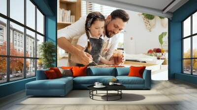 Delighted girl spending time with adorable father cooking baking together. Applying tomato sauce on fresh kneaded dough for pizza. Father teach daughter cooking prepare surprise for mother. Wall mural