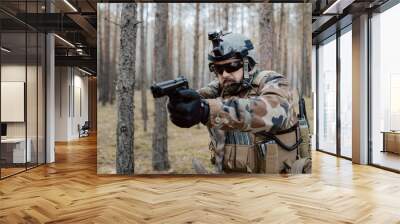 Portrait of a middle-aged bearded soldier in a Woodland military uniform and helmet, with headphones on his head holding a gun. Wall mural