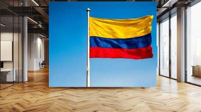 Colombia flag flying on pole against blue sky background  Wall mural