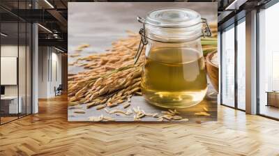 Rice bran oil in a glass jar with rice paddy grains beside it, isolated on white background. Showcasing the natural beauty and health benefits of this versatile ingredient Wall mural