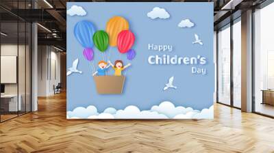 Happy Children's Day text with happy kids flying from hot air balloons on cloudy background in paper cut style. Can be used as greeting card or poster design. Wall mural