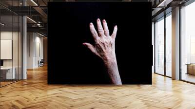 Open white old lady hand with palm facing down on a black background Wall mural