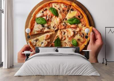 Overhead anonymous person taking slice of palatable seafood pizza with mushrooms and basil against white background Wall mural