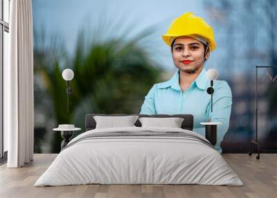 Close up portrait of beautiful female engineer wearing a protective helmet and looking at camera. Wall mural