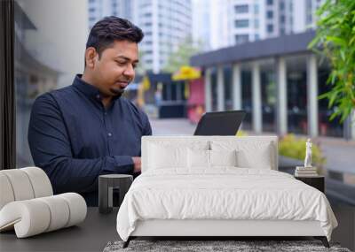 Young entrepreneur or Businessman working on laptop outside the office building. Wall mural