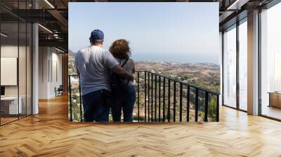 Fotografía de una pareja mirando el paisaje con el mar de fondo. Wall mural