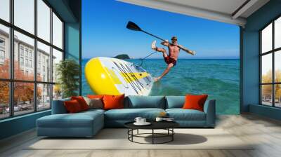 Tanned sportsman falling to sea water practicing supsurfing with paddle extreme sport leisure Wall mural