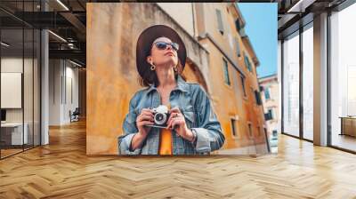 Attractive photographer with a retro camera outdoors Wall mural