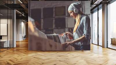 Young woman with headphones browsing vinyl records Wall mural