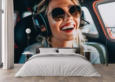 Cute and beautiful blonde woman smiling while flying a helicopter and enjoying the views Wall mural