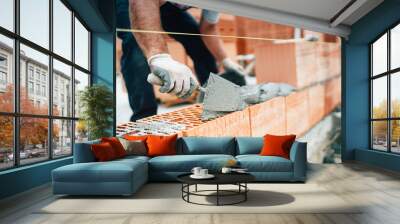 Professional worker using pan knife for building brick walls with cement and mortar Wall mural