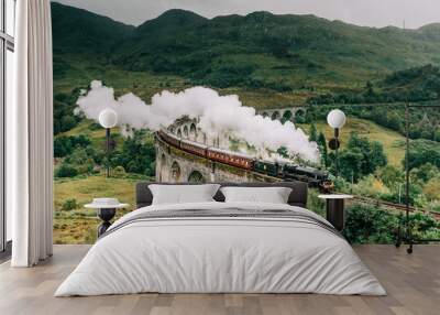 A steam train crossing the Glenfinnan viaduct in the Scottish Highlands made famous by the Harry Potter movies. The Jacobite steam train crossing the bridge with steam in Scotland United Kingdom Wall mural