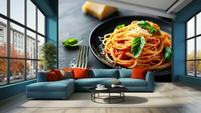 A plate of spaghetti with tomato sauce and basil. A fork on the plate. The plate is sitting on a black table. Wall mural