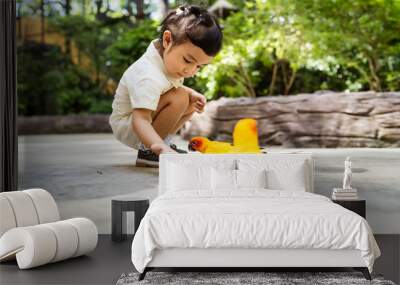 Asian little girl feeding birds on a hand in the park. Wall mural