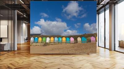 Traditional colourful English seaside scene beach huts beach and blue sky with pastel colours Wall mural