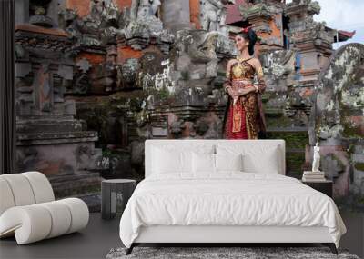 Beautiful balinese girl in traditional costume with a flower and a crown in her hair, and local temple Wall mural