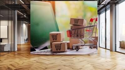 Shopping online concept - Parcel or Paper cartons with a shopping cart logo in a trolley on a laptop keyboard. Shopping service on The online web. offers home delivery.. Wall mural