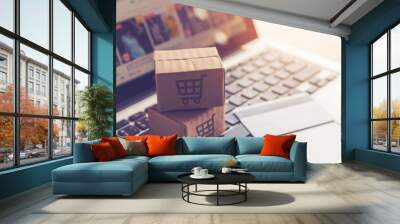 Shopping online. Cardboard box or parcel with a shopping cart logo in a trolley on a laptop keyboard payment by credit card and offers home delivery. Wall mural