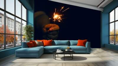 Woman hand holding a burning sparkler. Christmas and new year sparkler holiday background Wall mural