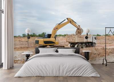 Yellow excavator machine loading soil into a dump truck at construction site Wall mural