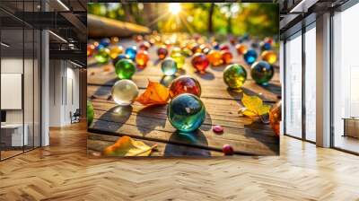 Colorful glass marbles scattered on a worn wooden floor, with a few rolling away, surrounded by scattered leaves Wall mural