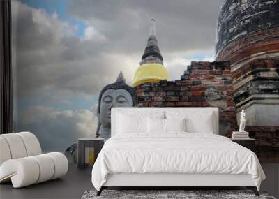 Stucco Buddha statue with ruins bricks on blue sky and cloud background. Wall mural