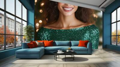 woman in a green sequined dress holding a present box near a Christmas tree smiling Wall mural