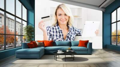 Attractive blond woman with a credit card and a tablet computer Wall mural