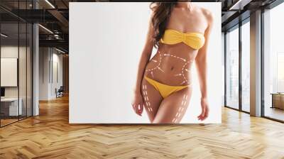 Beautiful woman with slim and sporty body in swimwear having arrows along her stomach and legs. Fat lose, liposuction and cellulite removal. Wall mural